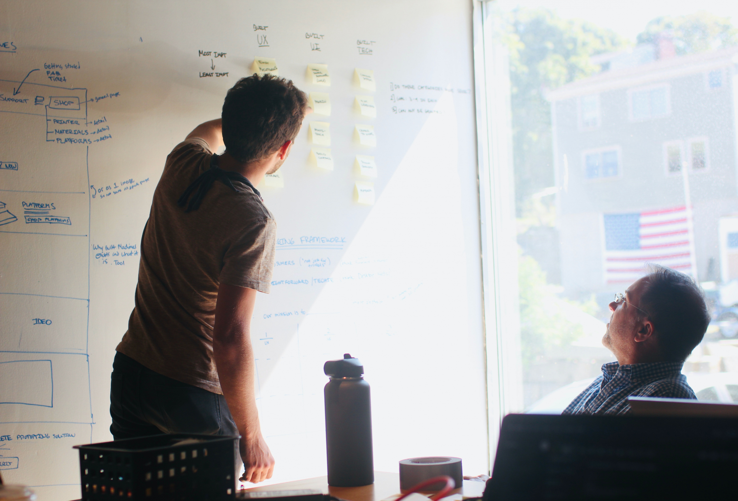 man in gray crew neck t-shirt standing near whiteboard